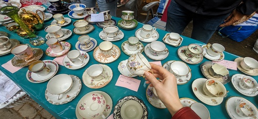 Besucherin stöbern auf dem Promenaden-Flohmarkt zwischen Porzellan und alten Schätzen.